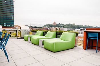 a terrace with green couches and chairs on a roof at Icon Apartments, Seattle, 98104